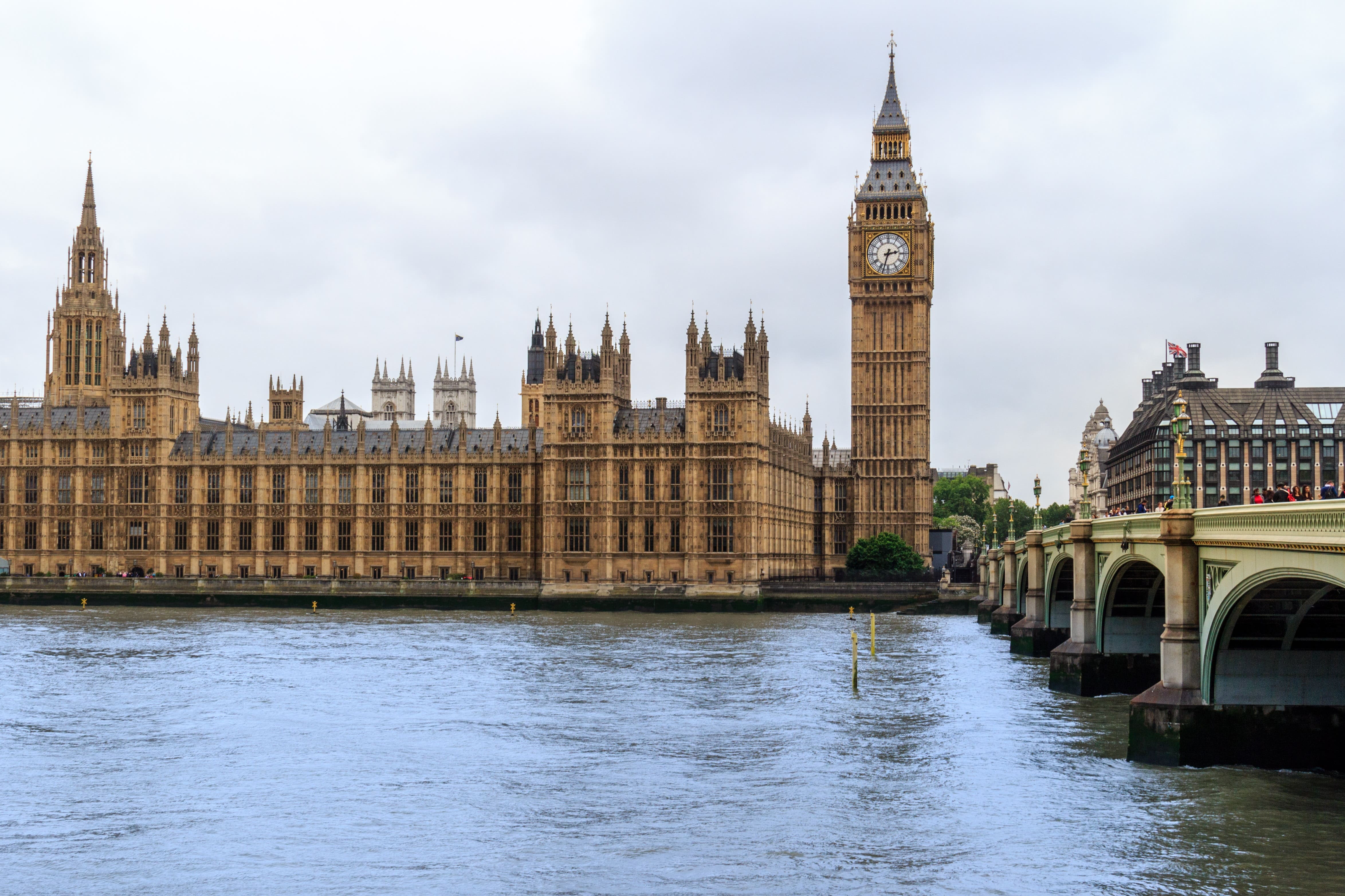 Vista do Palácio de Westminster e da torre do relógio em Londres, às margens do rio Tâmisa, com a ponte Westminster Bridge à direita.